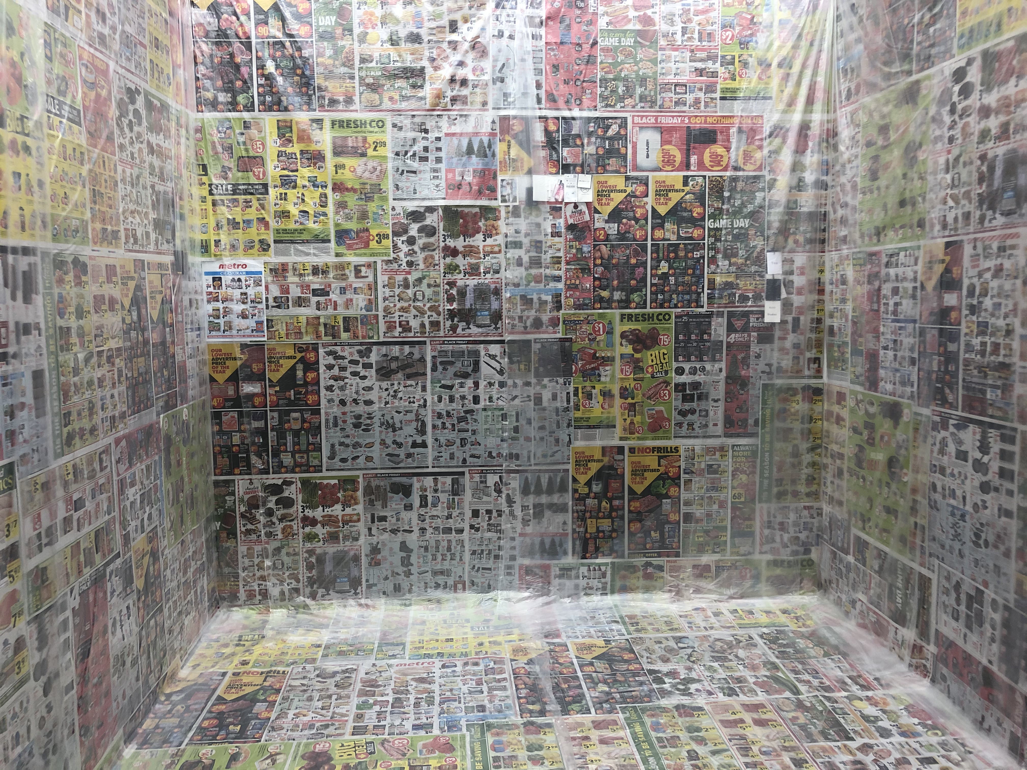 Photo of a small room wallpapered with grocery store flyers.